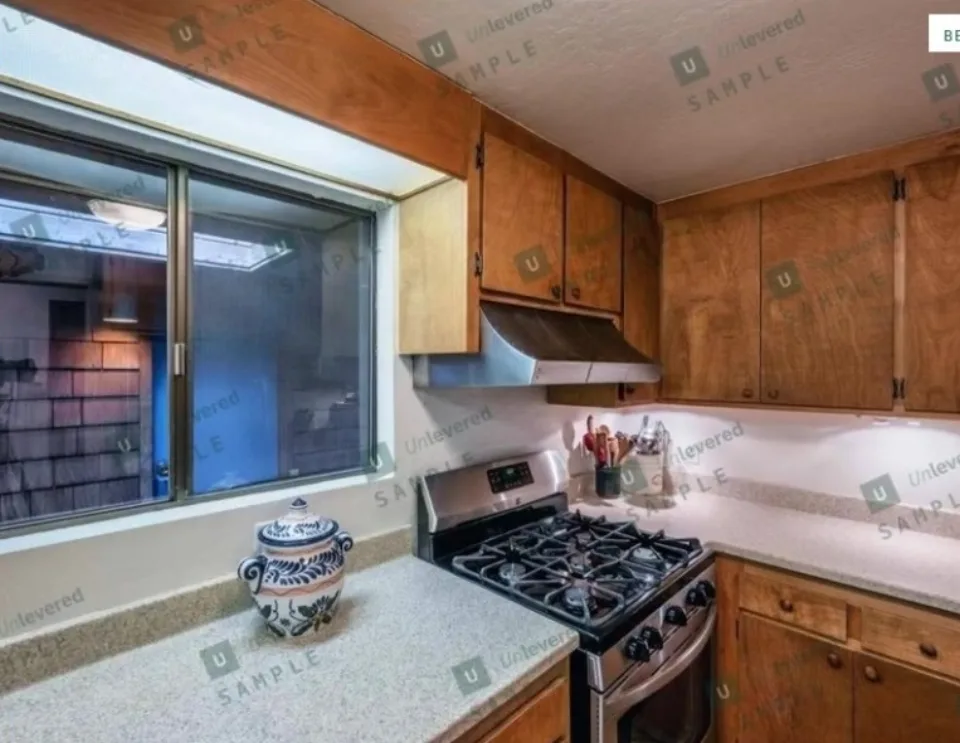 Kitchen before the remodel: wood cabinets, tile counters, and an older gas range